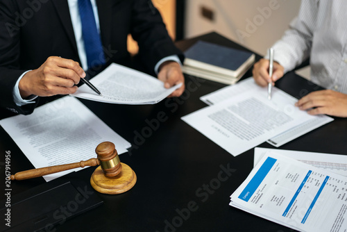 Two men are sitting at a table with papers and pens