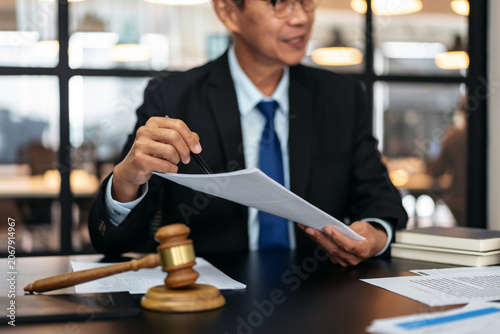 A man in a suit is holding a piece of paper and a gavel
