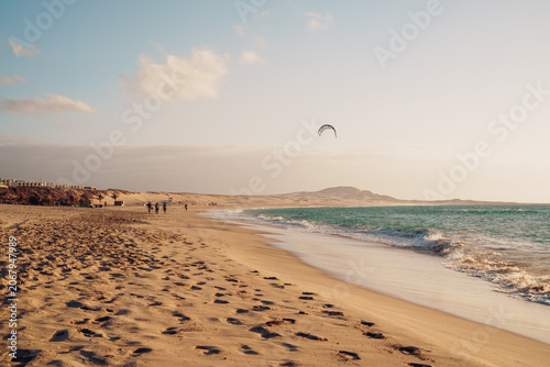 Fotografie Ocean coastline at golden hour with windsurfer silhouette at Chaves Beach, Cape