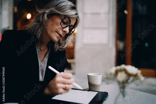 Foto Concentrated woman using stylus pen to sign digital document on tablet at cafe t