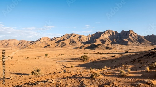 Desert landscape with mountains and sandy dunes under blue sky