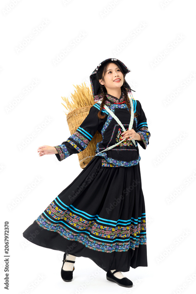 Obraz premium Smiling young woman in traditional ethnic costume carrying wheat basket