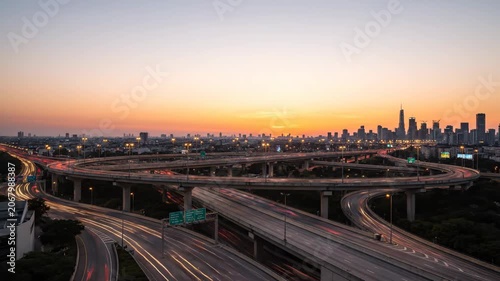 Dynamic Time-lapse of a Modern City Highway Interchange and Urban Skyline from Sunset to Night to Sunrise.