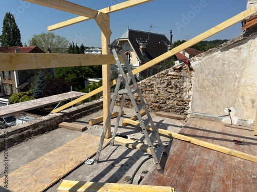 Construction site with wooden beams and ladder on rooftop