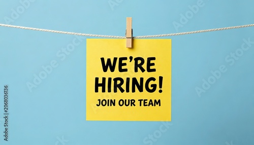 Yellow hiring sign with wooden clothespin on blue background