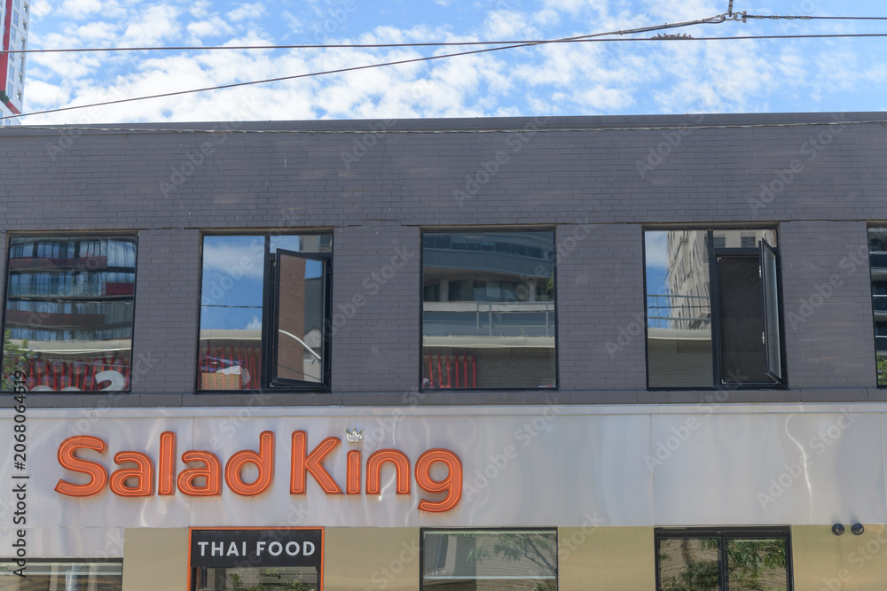 Naklejka premium exterior building facade and neon sign of Salad King, a Thai restaurant, located at 224 Queen St W, Toronto (McCaul St entrance)
