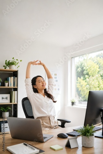 Woman stretching at desk with computer