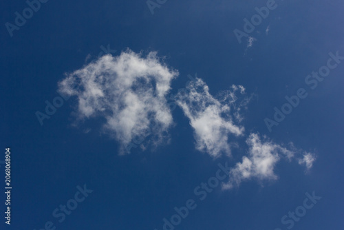 Small white cumulus clouds in a clear blue sky.