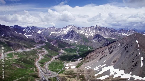 Winding Mountain Road Through Snow Capped Peaks and Alpine Valley