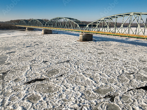 Metal bridge with traffic over a river with ice floes.