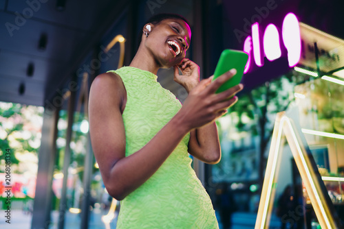 Cuadro en lienzo Overjoyed black woman holding green smartphone and laughing out loud near purple neon sign