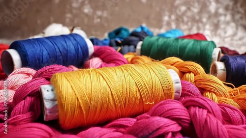 A vibrant collection of colorful embroidery threads is artfully arranged on a textured surface.