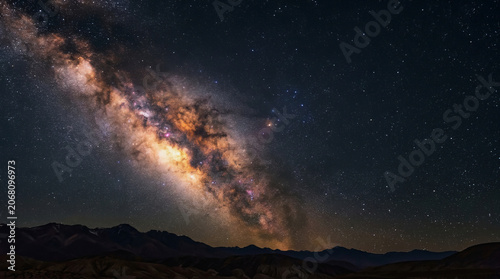 Milky Way galaxy arches over dark mountain range in desert night sky with stars and cosmic dust clouds visible above rugged landscape silhouette