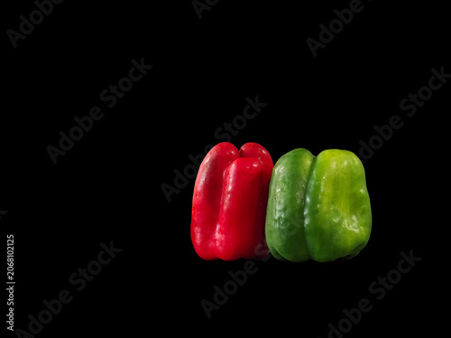 Two bell peppers sit side by side on a dark background with bright colors that catch the eye