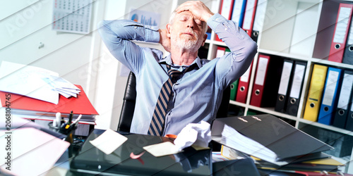 Photos Overworked businessman sitting at a messy desk, geometric pattern