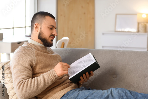 Handsome young man reading ...