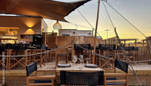 Elegant Outdoor Restaurant Terrace at Sunset with Wooden Tables and Warm Lighting