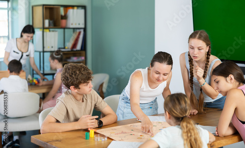 Group of teens playing board game. Teenagers have fun during meetings and gatherings, enthusiastically and excitedly fulfill conditions of game