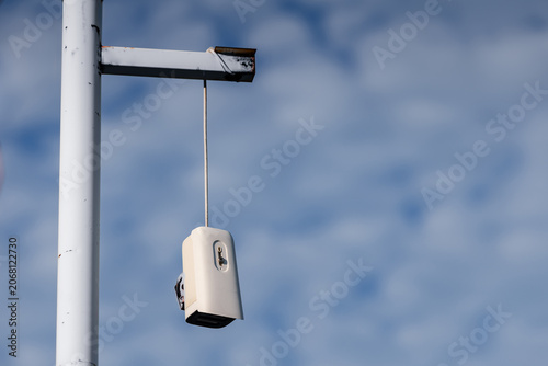 фотографія Broken CCTV camera hanging from pole against cloudy sky