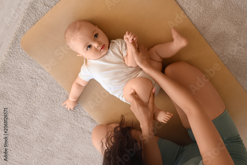 Sporty young woman with her little baby on yoga mat at home, top view