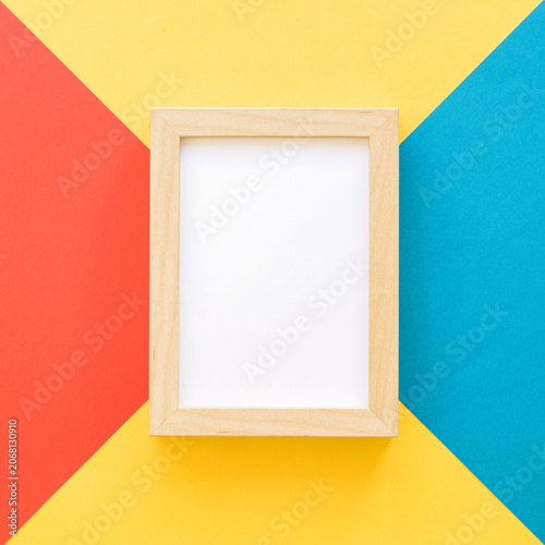 Wooden picture frame on colorful geometric background