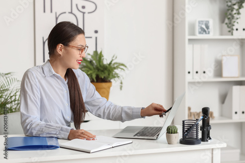Young Asian businesswoman working with laptop and notebook at desk in office