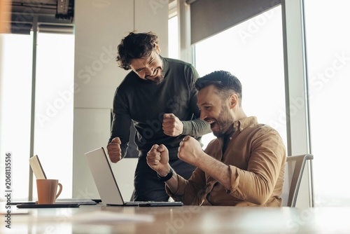 Vászonkép Joyful Caucasian Men Celebrating Achievement Together In Modern Office Environment, Engaging In Teamwork And Collaboration, Smiling And Supporting Each Other In Success
