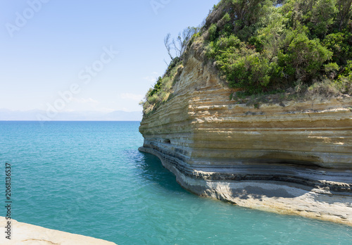stunning layered clay cliffs meeting vibrant turquoise sea water under a clear blue sky, a perfect mediterranean coastal landscape for summer travel concepts.