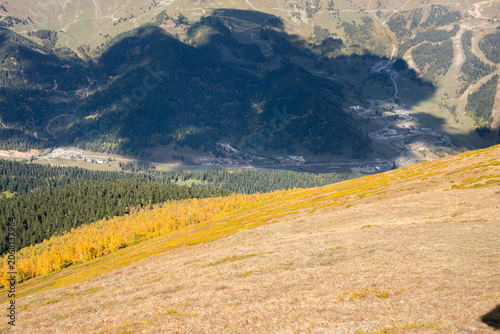 Horizontal high mountain valley with autumn forest shadows and winding roads in Arkhyz Karachay Cherkessia Russia.
