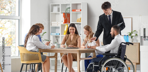 Foto Young man in wheelchair using laptop with human resources commission during job