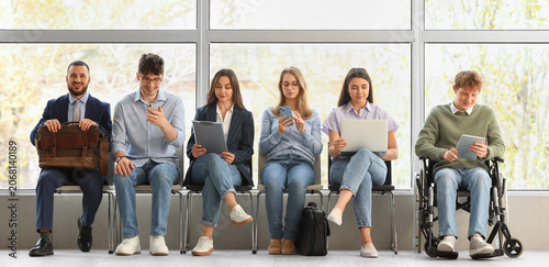 Quadro su tela Young job applicants with man in wheelchair waiting for interview at office