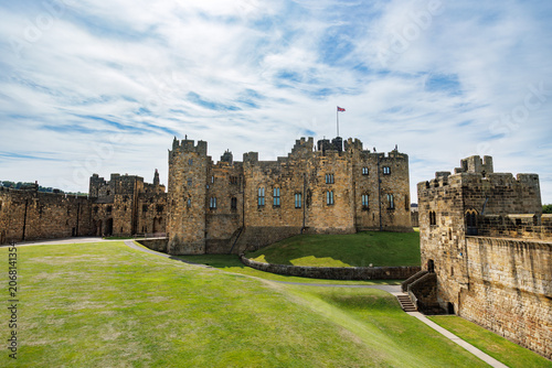 Tableau sur toile Historic medieval Alnwick castle on grassy lawn under blue sky