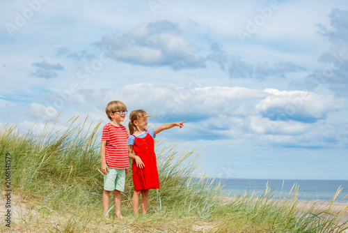 Photos Two children boy and girl explore a beach pointing at oceanside