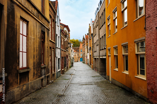 Obraz na plátně Narrow cobblestone street between brick townhouses in Europe