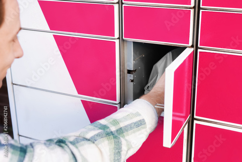 Fotografie Man picking up a parcel from an open self-service locker compartment