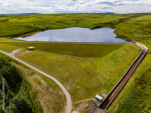 Viewing a scenic water reservoir and green hills from above on a sunny day