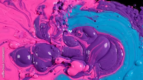 Thick Pink and Purple Paint Pouring and Swirling into Blue Liquid, Macro Abstract Fluid Art on Black Background