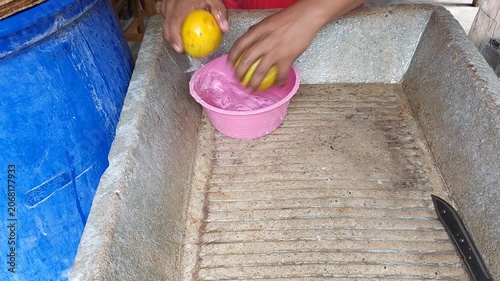 Washing Two Organic Oranges under Running Water in Concrete Basin