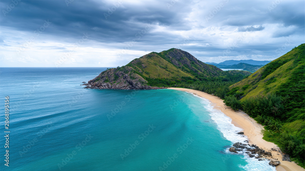 Fototapeta premium A breathtaking aerial view of a pristine tropical beach with turquoise waters meeting a sandy shore, bordered by lush green hills under a dramatic cloudy sky
