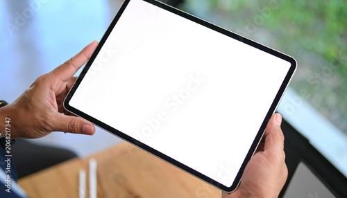 A businessman holds a mockup. iPad digital tablet with blank screen Mockup replaces your design mockup in the office. gen ai