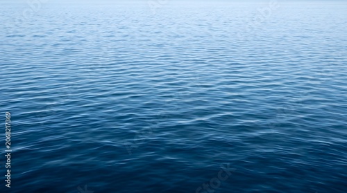 Calm ocean waves gently ripple on the surface of the deep blue water.
