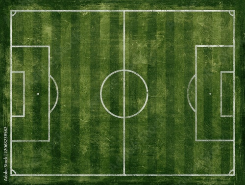 Top-down aerial view of a weathered, textured green soccer field with white lines