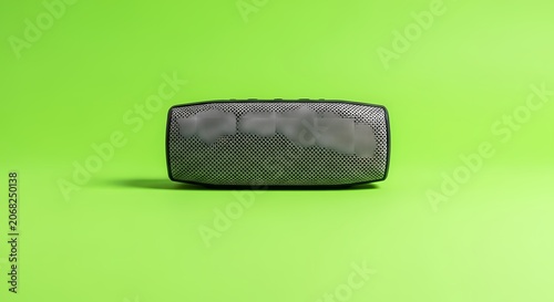 Compact Portable Speaker with Grille Detail on Vibrant Green Background