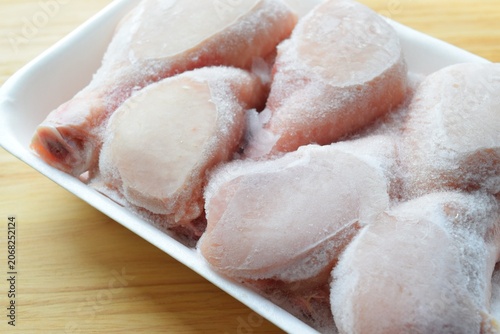 Raw chicken legs. Close-up of frozen chicken drumsticks in a white container