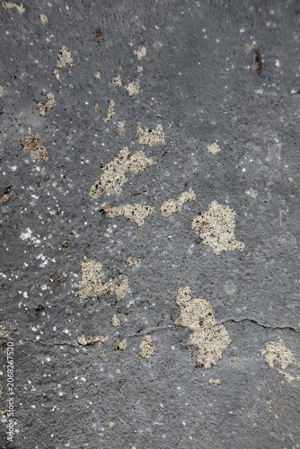 Close-up texture of dark grey asphalt or concrete surface with light chipped patches 