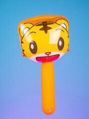Close-up of an inflatable stick with a tiger-shaped inflatable head on a purple background. Bold and playful, perfect for fun moments and striking photos.