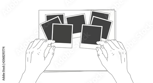 A pair of hands arranging several blank polaroid photos on a flat surface.