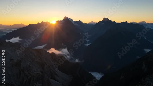 Golden sunrise illuminates the jagged peaks of a high mountain range