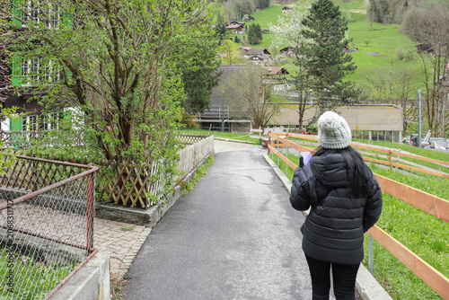 Person walking on paved path in rural village setting.
