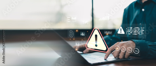 Foto Cybersecurity warning concept with business professional using laptop and digital alert interface, representing risk management, data protection, threat detection, system security and compliance